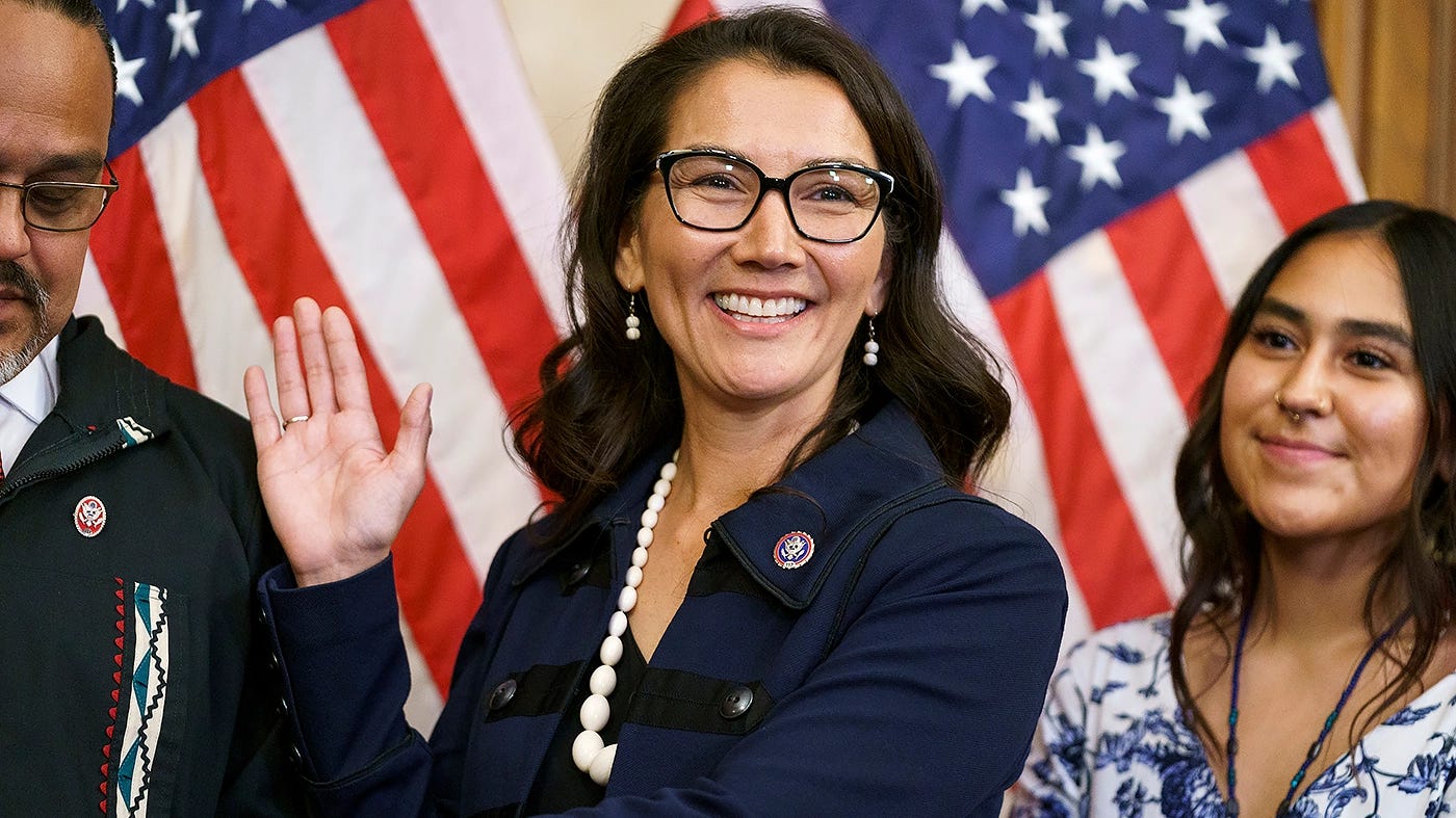 Congresswoman Mary Peltola raises her right hand and takes the oath of office in front of an American flag.