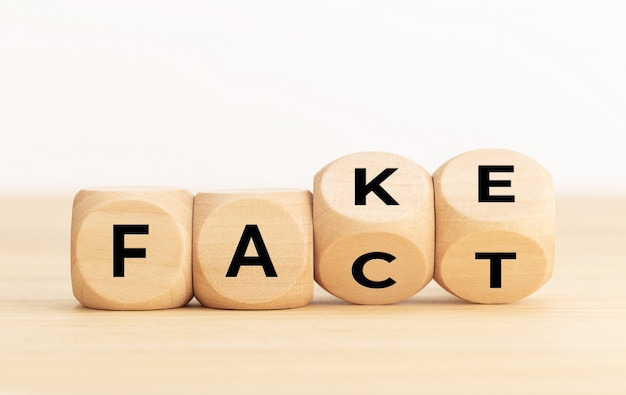 Turning wooden dice with word fake and fact Premium Photo