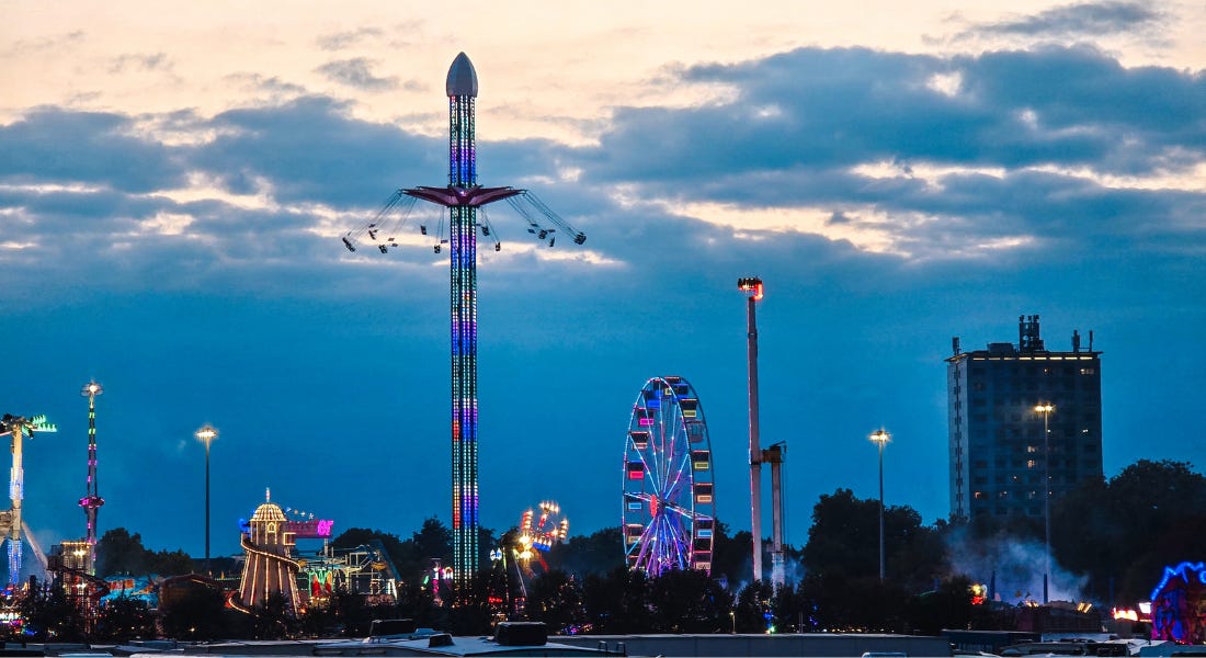 A sunset shot of a funfair with a tower, a helter skelter, and a ferris wheel A sunset shot of a funfair with a tower, a helter skelter, and a ferris wheel