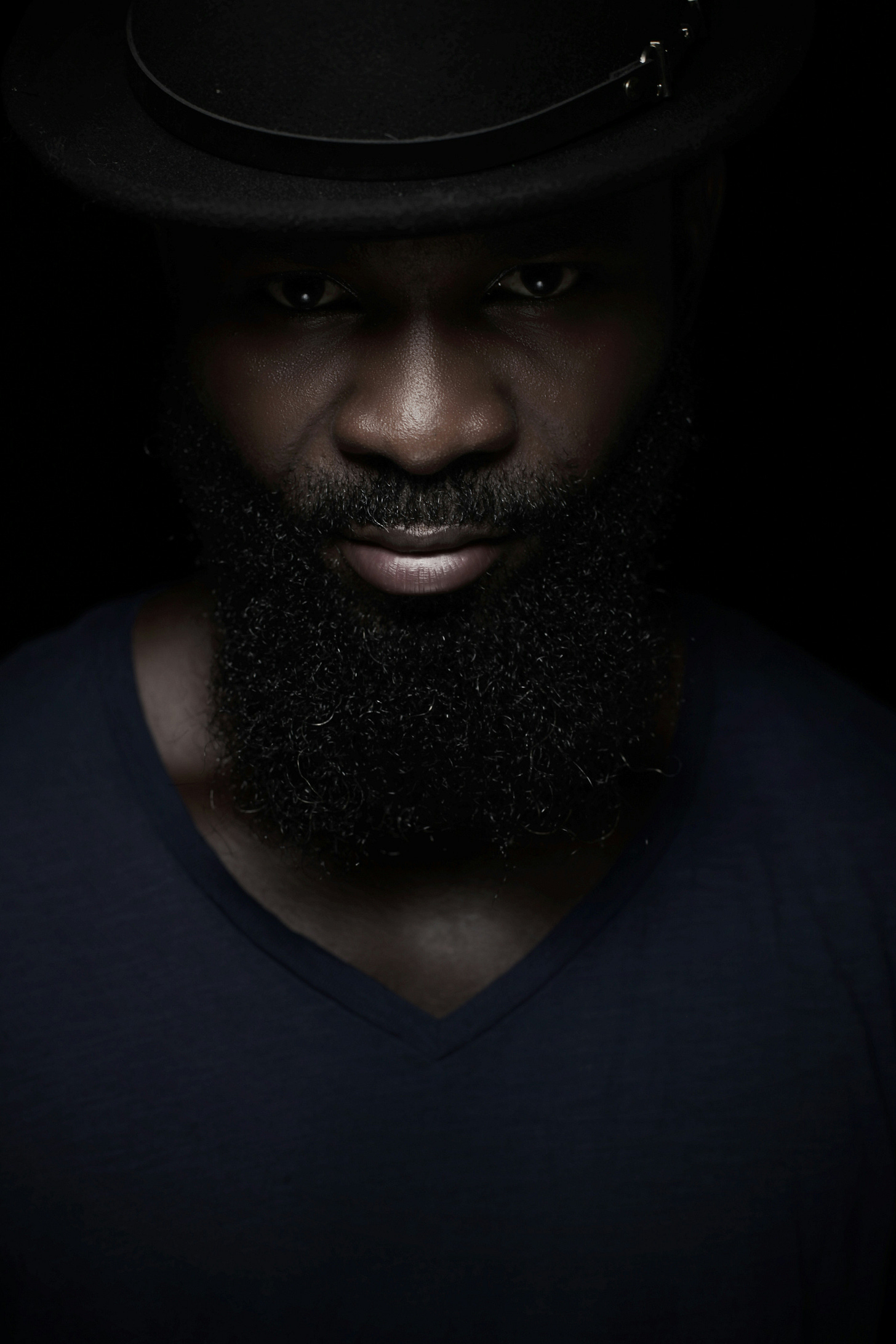 Portrait of a contemplative Black Gen X man in a dark hat and V-neck shirt, symbolizing resilience and midlife transformation.