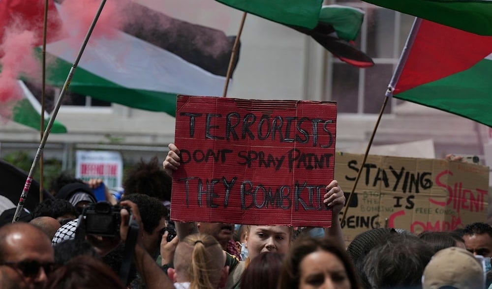 A demonstrator hold up a red painted placard during a protest by Palestine Action group in London, Monday, June 23, 2025. (AP)
