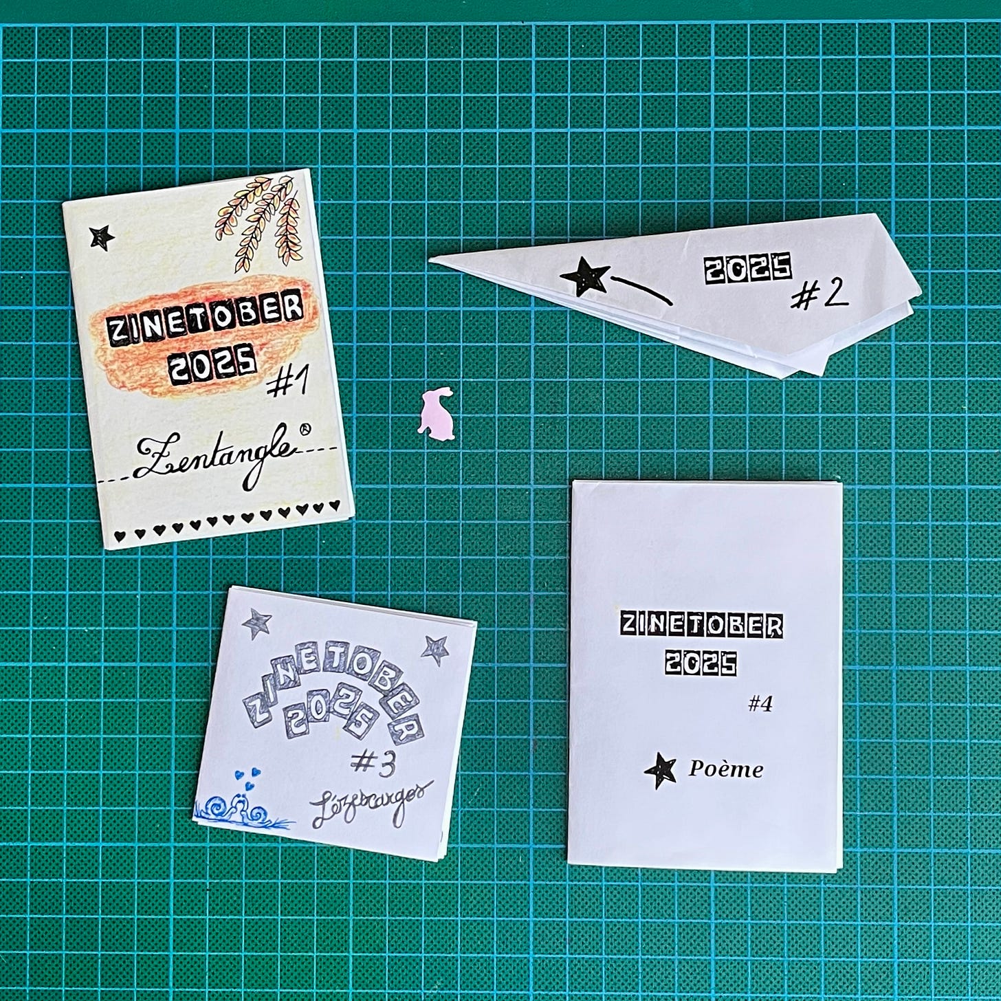 Photo des 4 zines créés par ijin : 2 mini zines format classique, un plié en avion en papier, un pliage mini zine mais 7 x 6,5 cm.