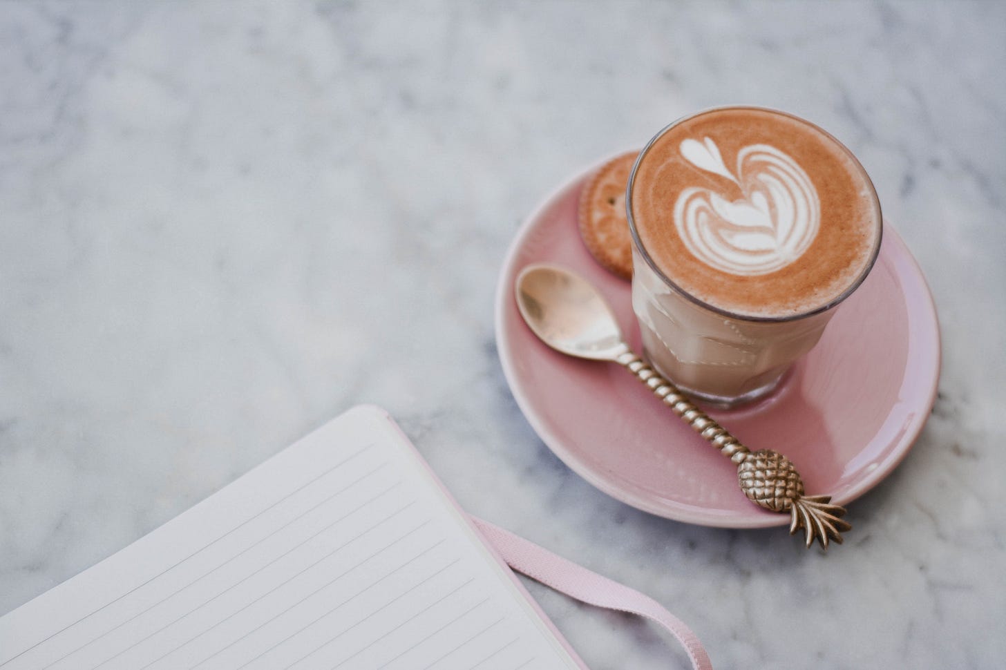 pink coffee cup next to open journal