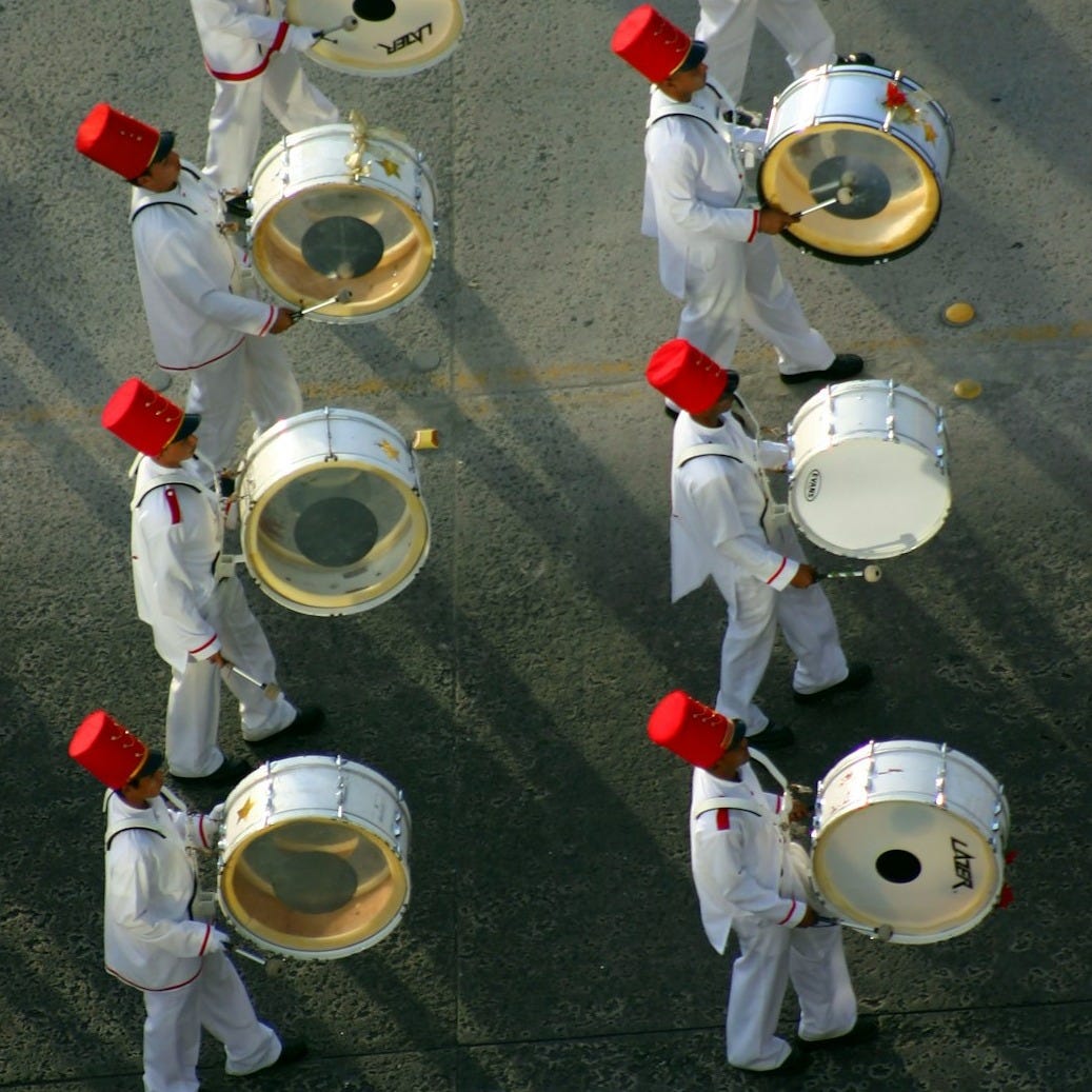 a group of men in white uniforms playing drums