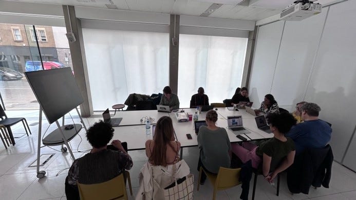 Photo of AI in the Street project members in a meeting, sat at a large table and viewing a display.