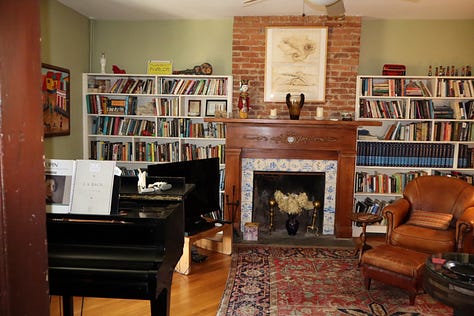 A road sign, a house number, a gate with stone pillars, a parlor with books and piano, a bedroom with writing desk
