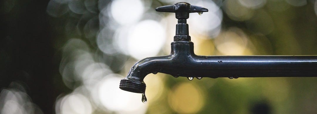 tilt shift lens photography of black steel faucet