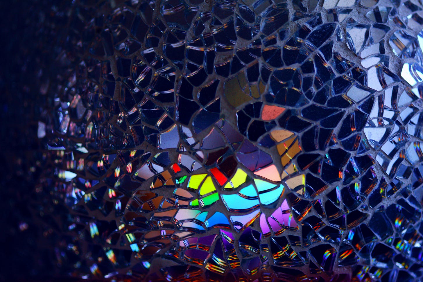 photo of a broken mirror where some of the shards are reflecting rainbow-esque colors