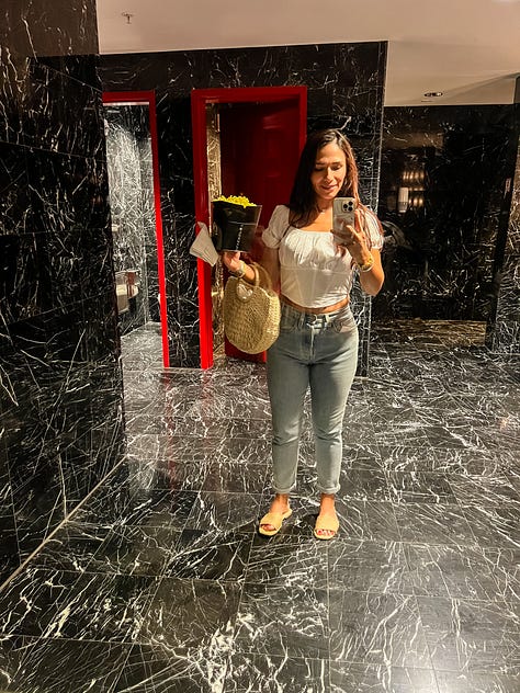Selfie of woman in a latticed chair, selfie of woman and her parents walking to the beach, selfie of woman and her parents at the beach, selfie of woman with sunglasses and hat, photo of a dog sleeping curled up on a fleece blanket on a bed, mirror selfie of a woman in a movie theater bathroom, photo of a lush banyan tree with sunlight seeping through, selfie photo of father and daughter in a living room, photo of a vehicle's dashboard and front windshield with a dark sky and rainbow arch in the distance