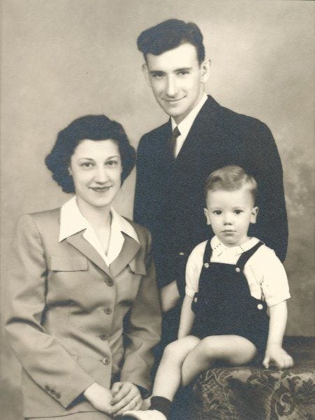This may contain: an old black and white photo of a man and woman with a baby sitting on a suitcase