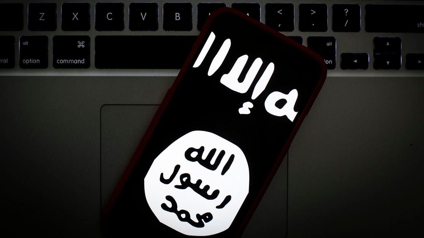 Photo of a phone screen showing the black and white ISIS logo as it rests on a keyboard Photo of a phone screen showing the black and white ISIS logo as it rests on a keyboard