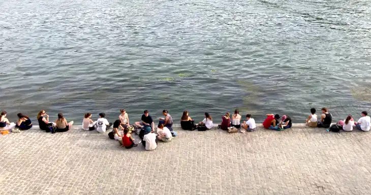 Phot of young people sitting by the river Seine in Paris. Phot of young people sitting by the river Seine in Paris.