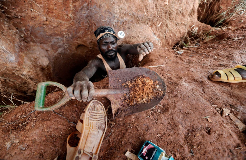 An informal gold miner carries a shovel as he climbs out from inside a gold mining pit at the site of Nsuaem-Top, Ghana No...
