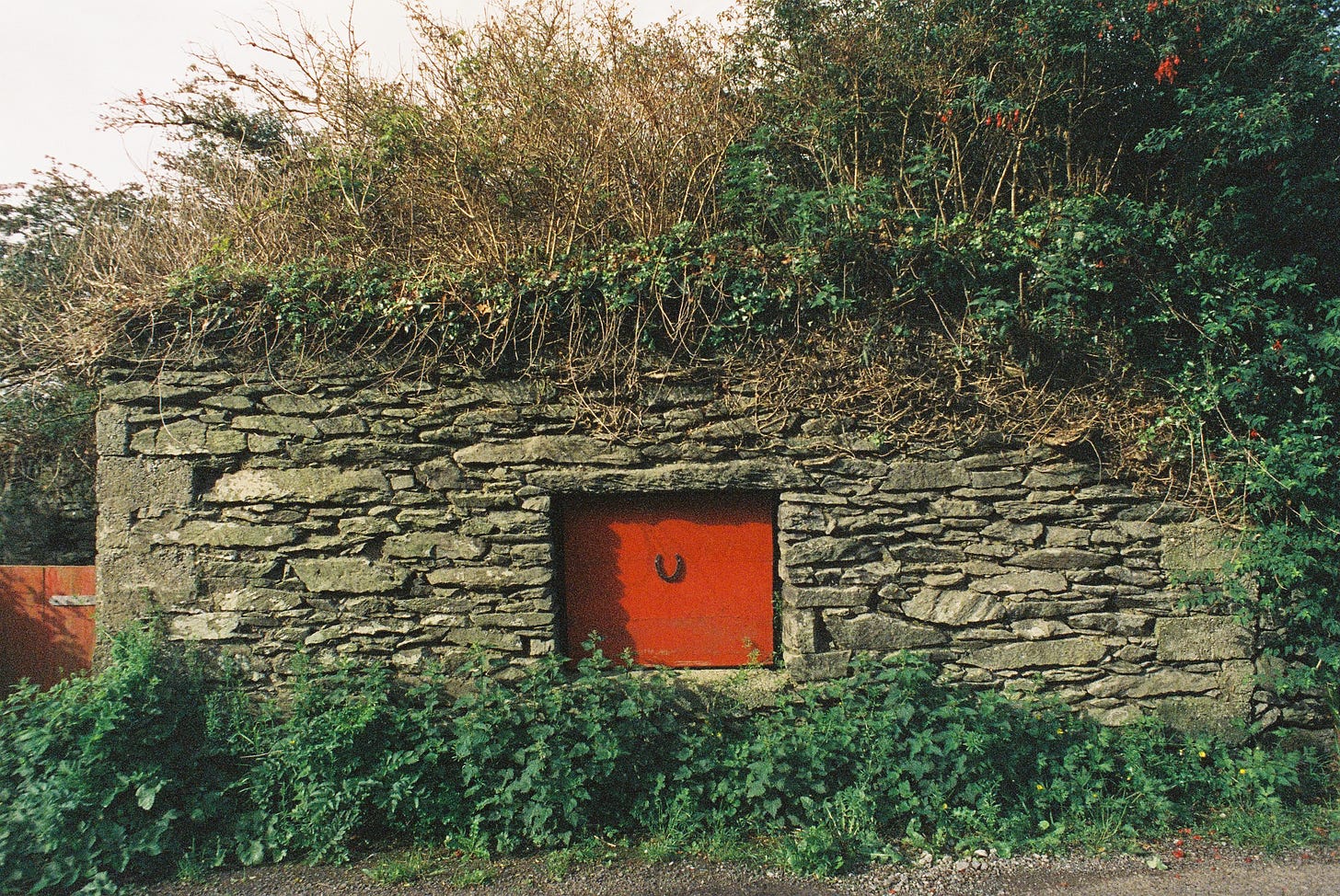 Red door with upturned horseshoe on old stone structure