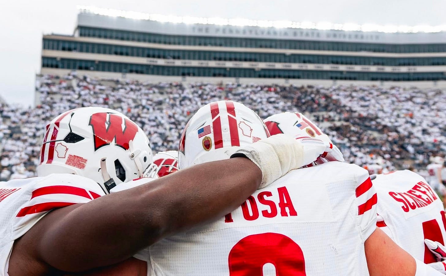 Wisconsin linebacker Mason Posa huddles with teammates on the field at Beaver Stadium.