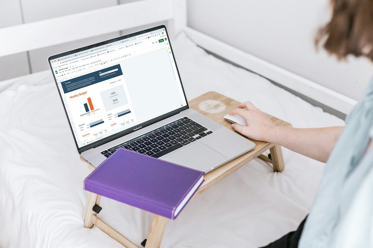 Person using a budgeting spreadsheet on a laptop while working from bed with a notebook nearby. Photo by Sincerely Media on Unsplash