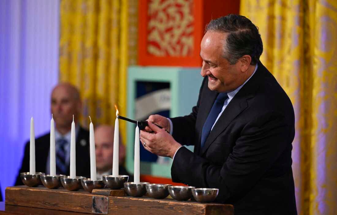 Second gentleman Doug Emhoff lights the first flame on a Menorah candle during a Hanukkah reception in the East Room of the White House on Dec. 11, 2023.