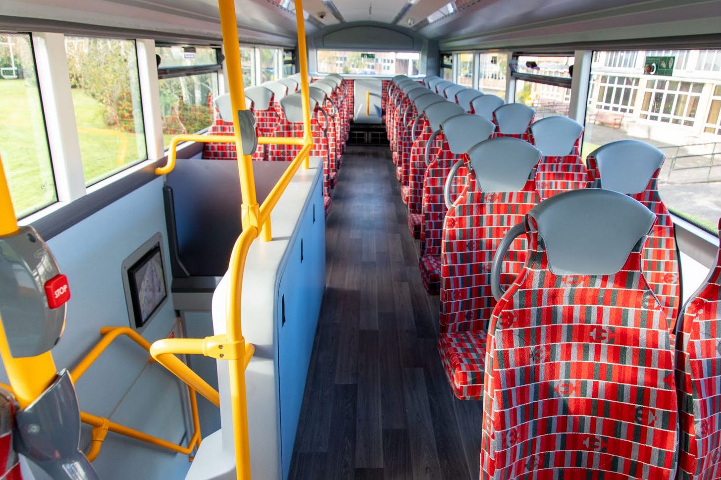 Photo of upper deck of bus with London red bus moquette and orange grab rails.