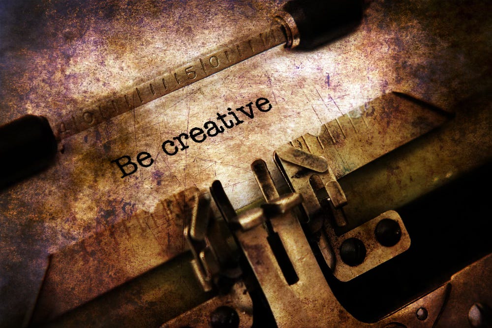 Sepia colored image of a manual typewriter - The page says Be creative