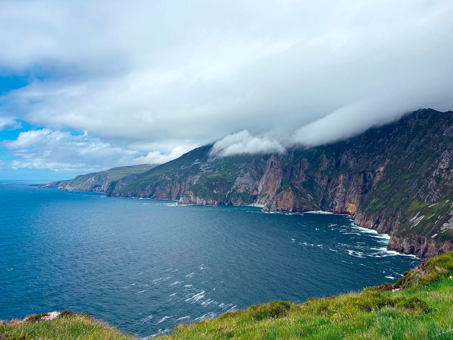cliff with low fog hovering its top, with waves below cliff with low fog hovering its top, with waves below