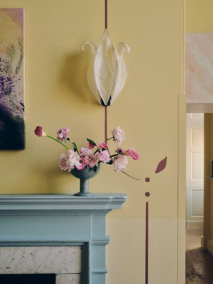 This may contain: a vase filled with flowers sitting on top of a table next to a fire place