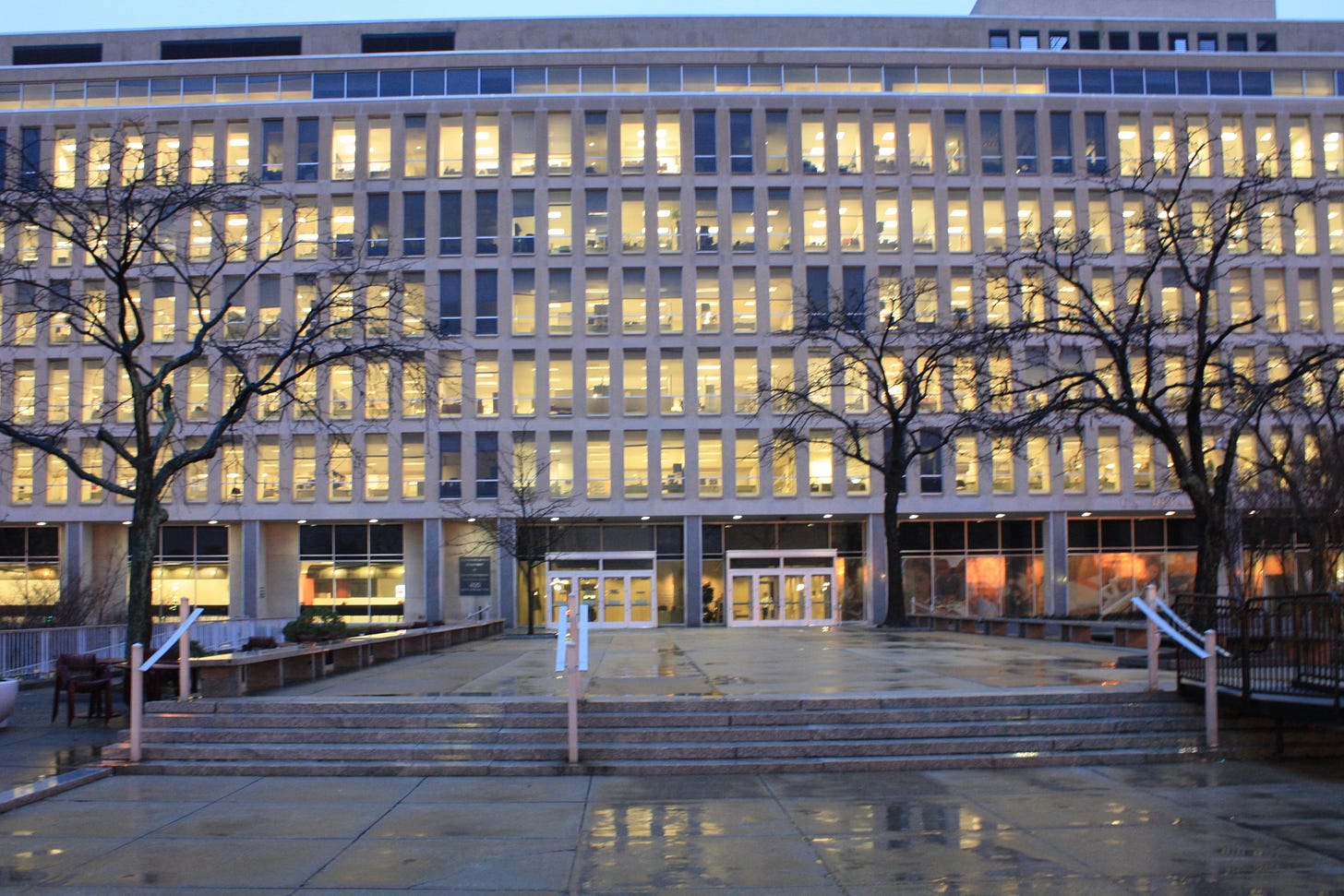the rectangular windows of a government agency building in Washington,DC glow in the dusk