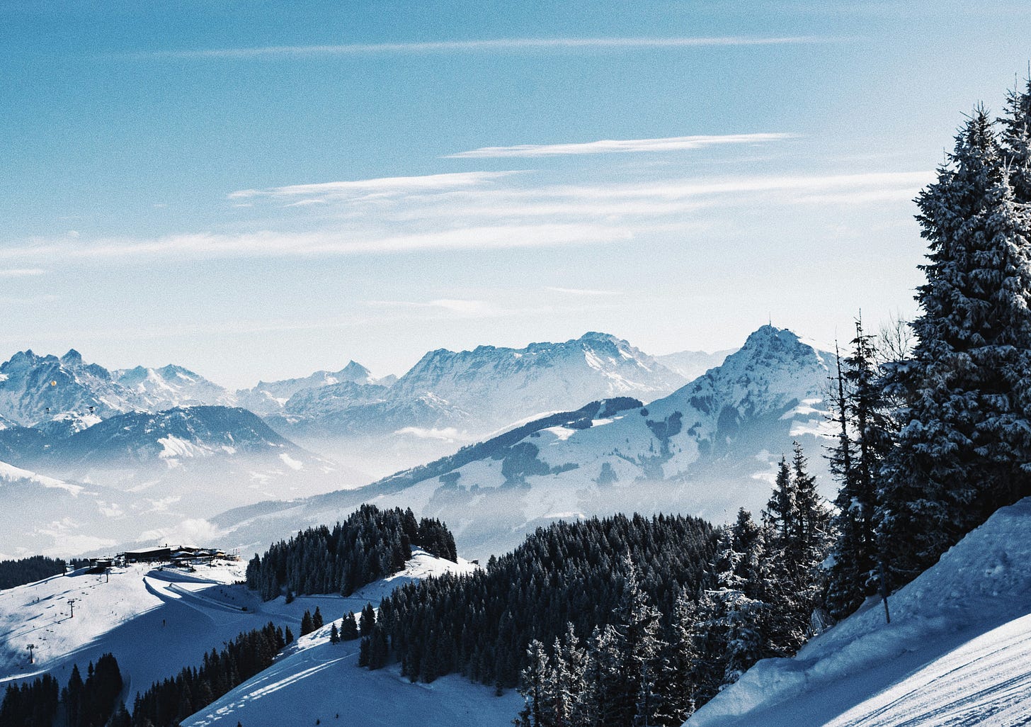 A majestic view of snowy mountains and pine trees against a clear blue sky