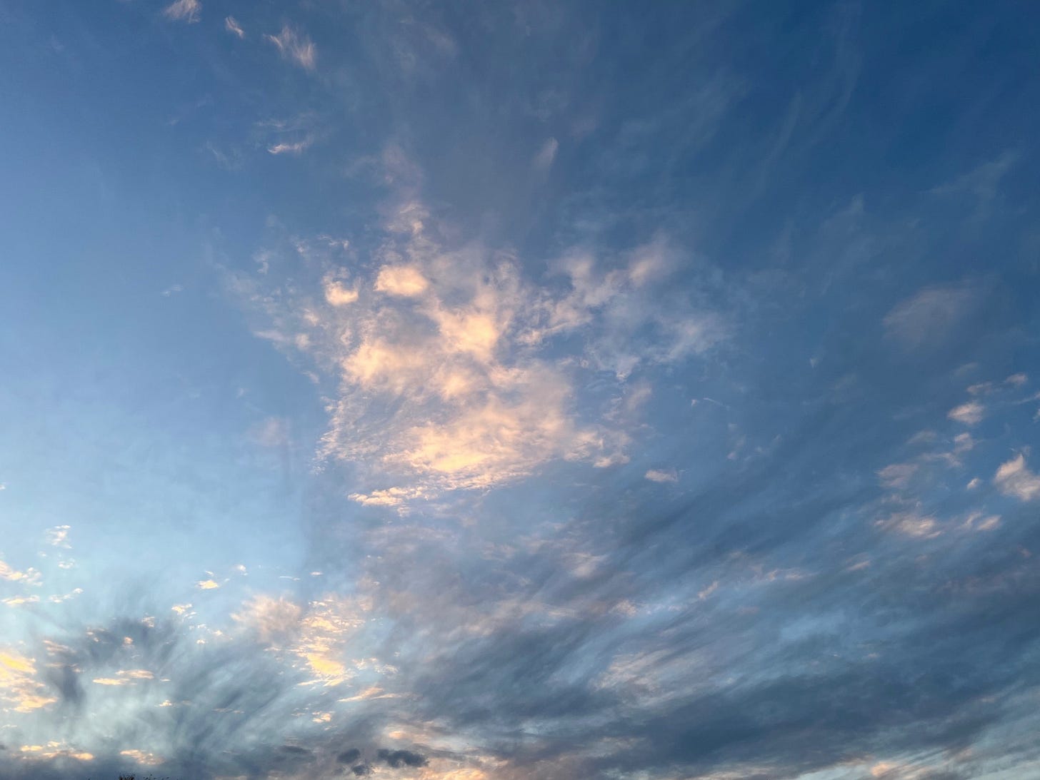 very dramatic clouds in a blue sky. one of the cloud clusters resembles a heart shape
