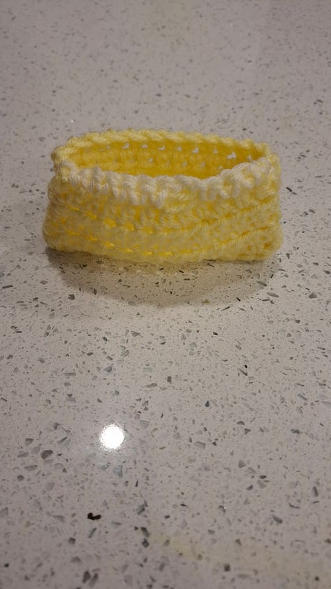 yellow bookmark, pile of crocheted items, rainbow book cozy, yellow pocket, blue coaster, set of pockets