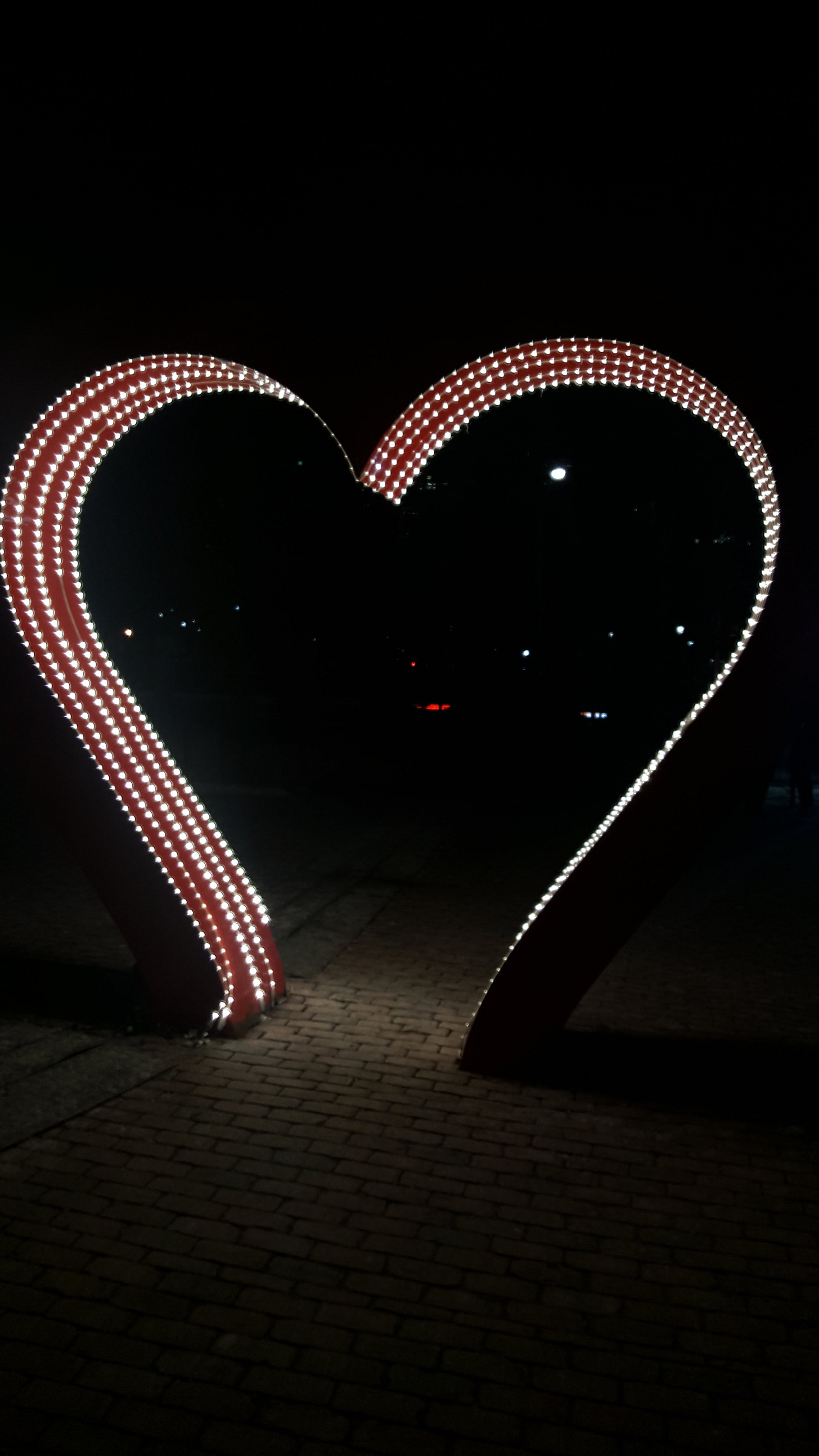 A lighted structure in the shape of a heart. It's aglow in the darkness of night.