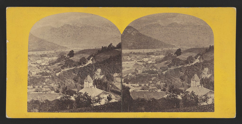 a black and white photo of an aerial view of a Swiss village with mountains in the background