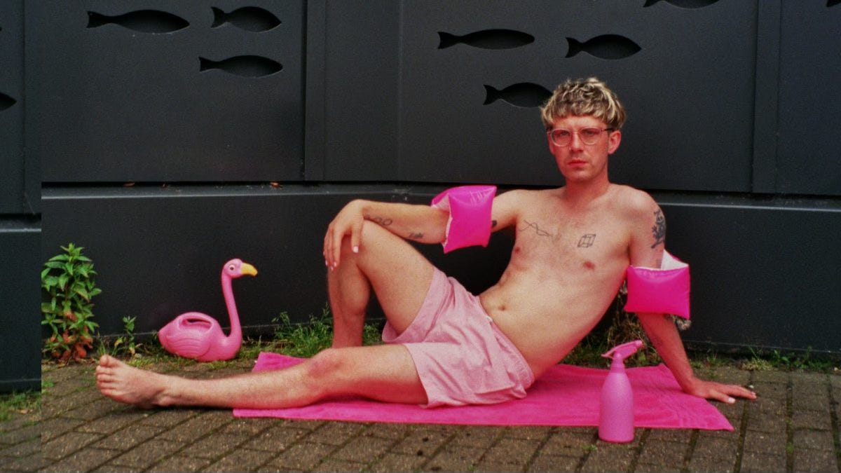 Man in pink swim shorts lounging on a pink towel