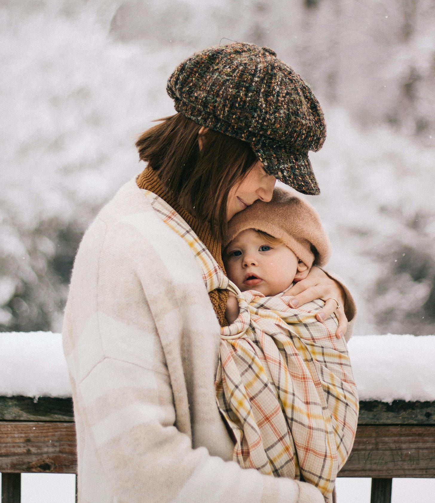 Free Heartwarming outdoor photo of a mother holding her baby in a snowy landscape, capturing a serene winter moment. Stock Photo