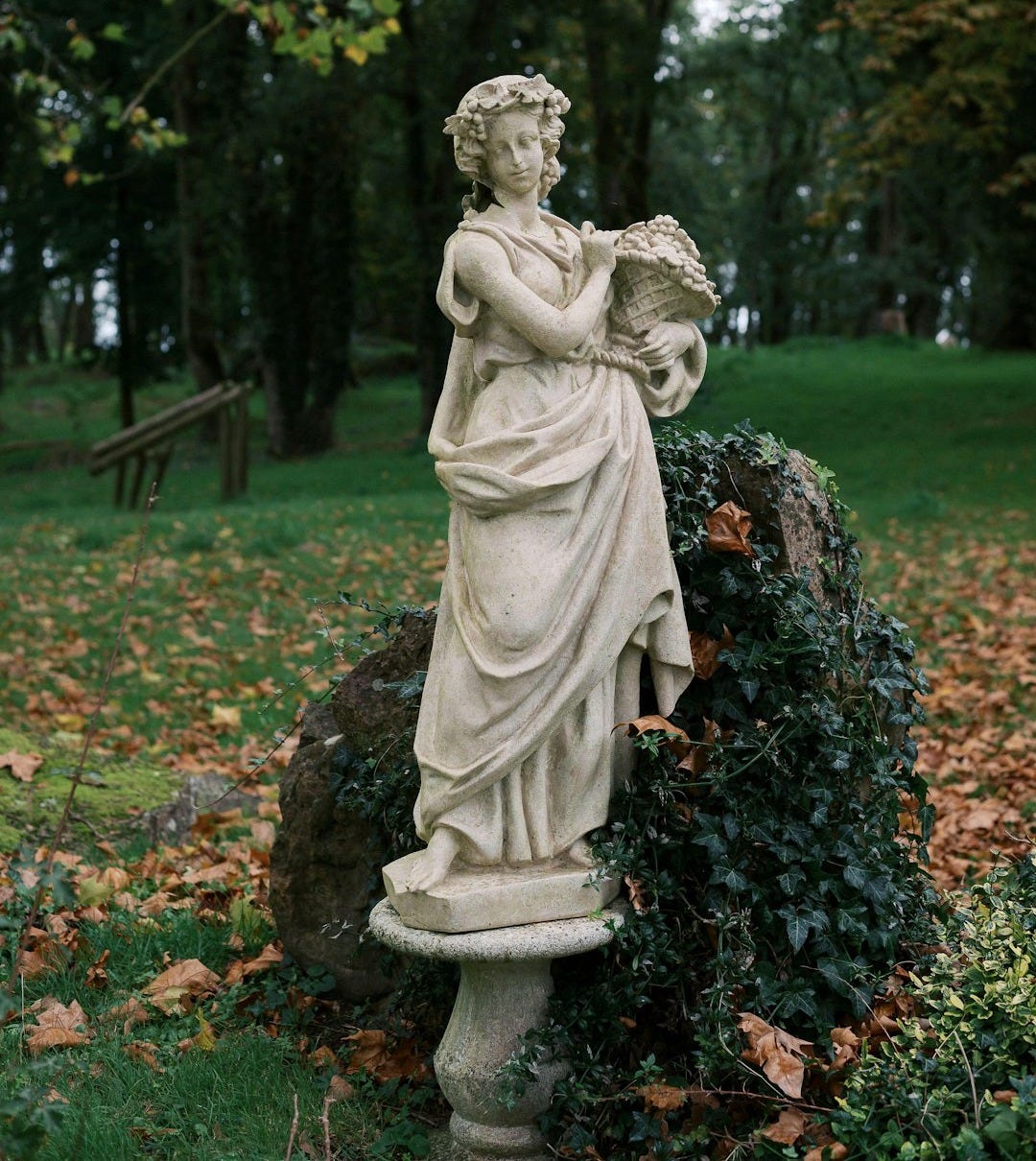 A statue of a woman holding a book in a park
