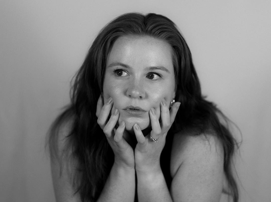 A young woman rests her chin on her hands.