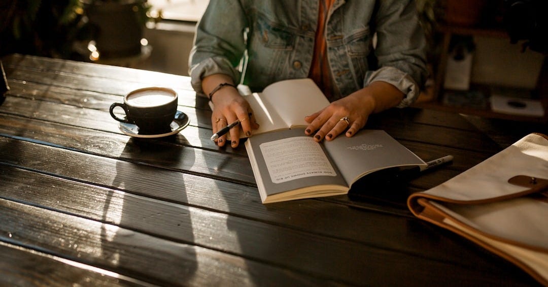 person opening notebook on brown wooden table