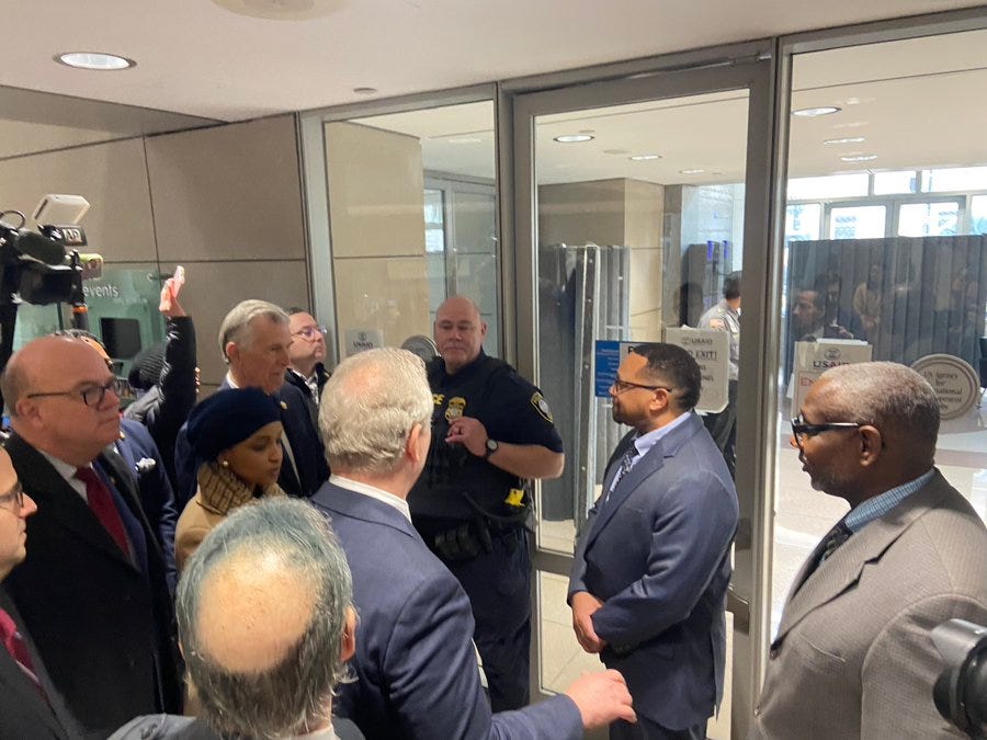 Members of Congress clustered around a security guard who denied the access to the USAID Building Members of Congress clustered around a security guard who denied the access to the USAID Building