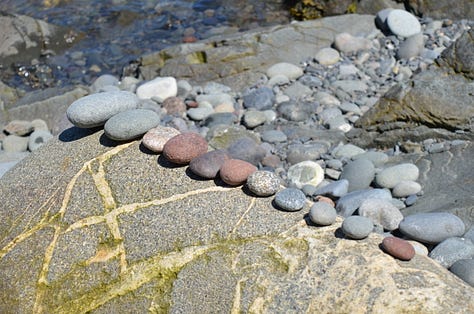 Lighthouse in Maine with rocky beaches and children playing.