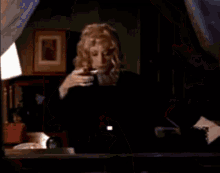 a woman is holding a glass of wine and a spoon in her hand . a woman is holding a glass of wine and a spoon in her hand .