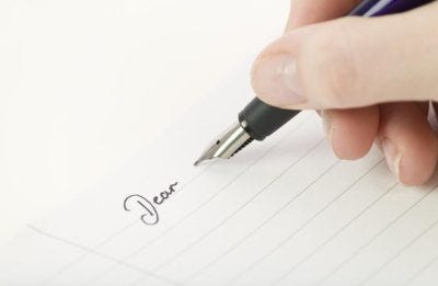 Someone writing a letter on lined paper