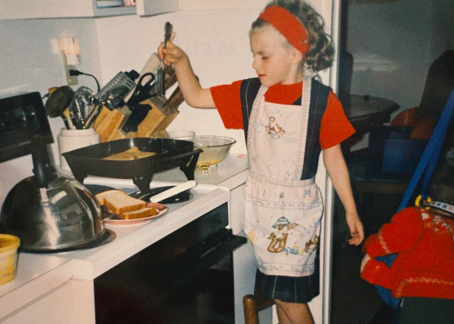 young child cooking french toast at stove