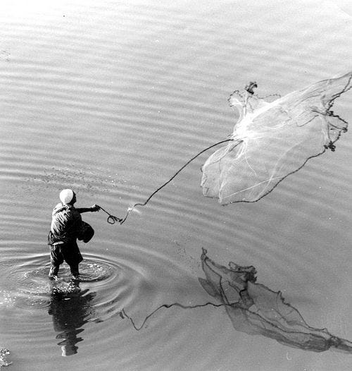 Black and white photo depicting fisherman casting a net into the Tigris river.