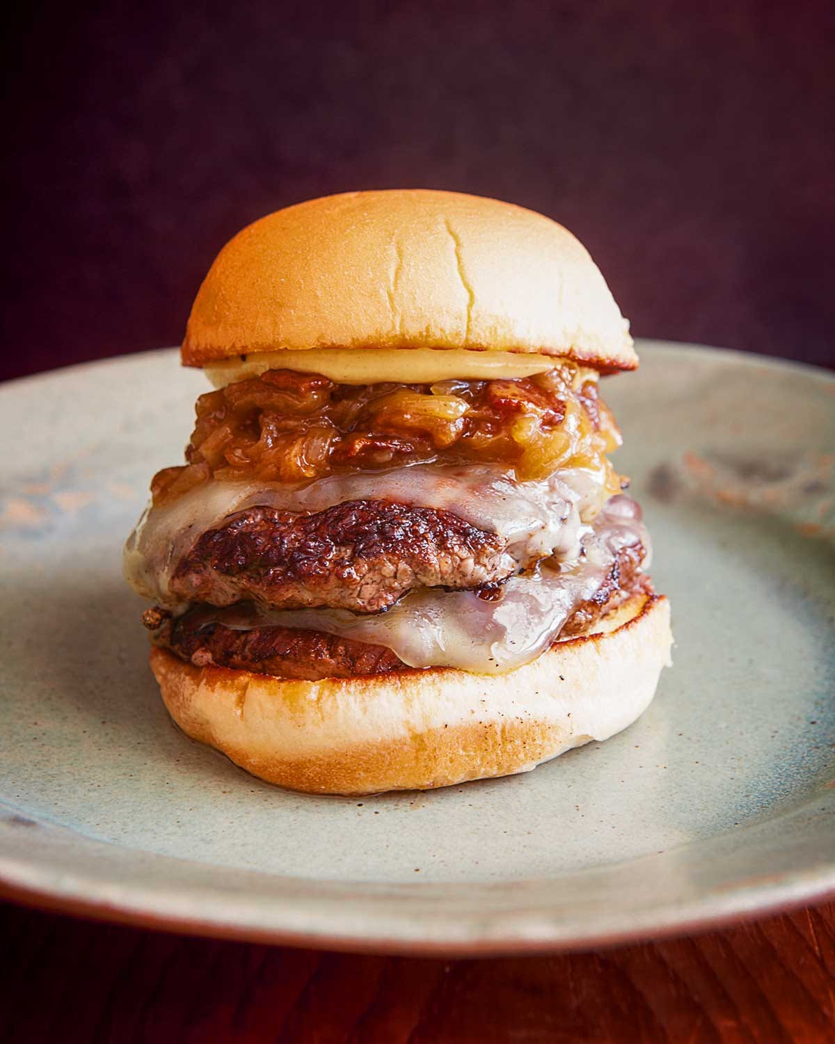 A copycat Shake Shack  roadside double-patty burger with Swiss cheese and beer-simmered bacon onions on a bun.