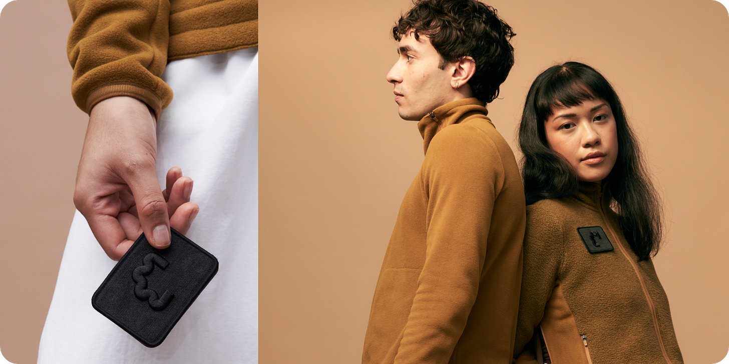 Two images. Left image closeup of model's hand and torso, holding an Early Majority clothing tag. Right image has two models back-to-back from torso up, wearing caramel colored Early Majority zip-ups.