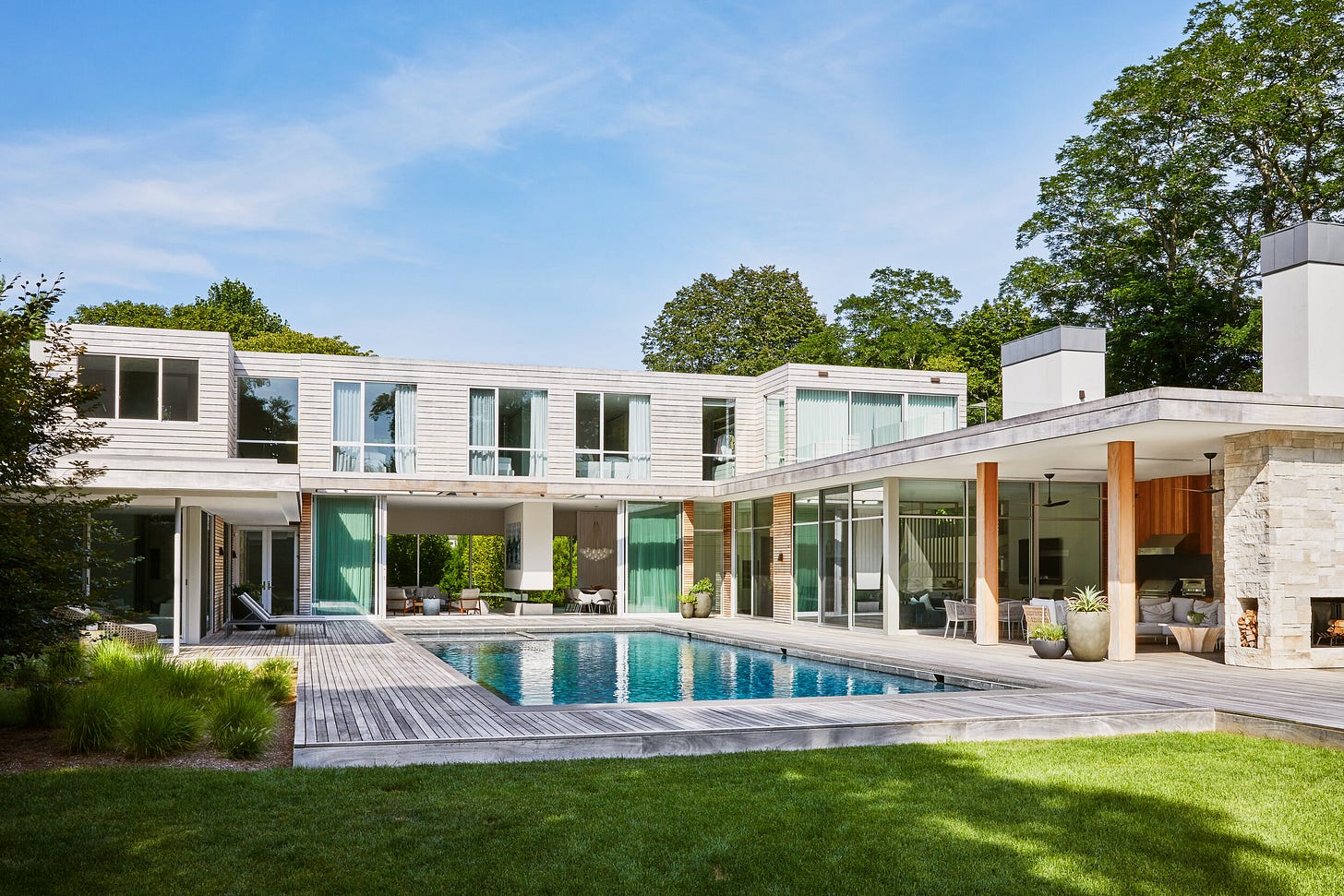 Swimming pool with open glass sliding doors and outdoor kitchen with ceiling fans, outdoor heater and Indiana limestone fireplace.