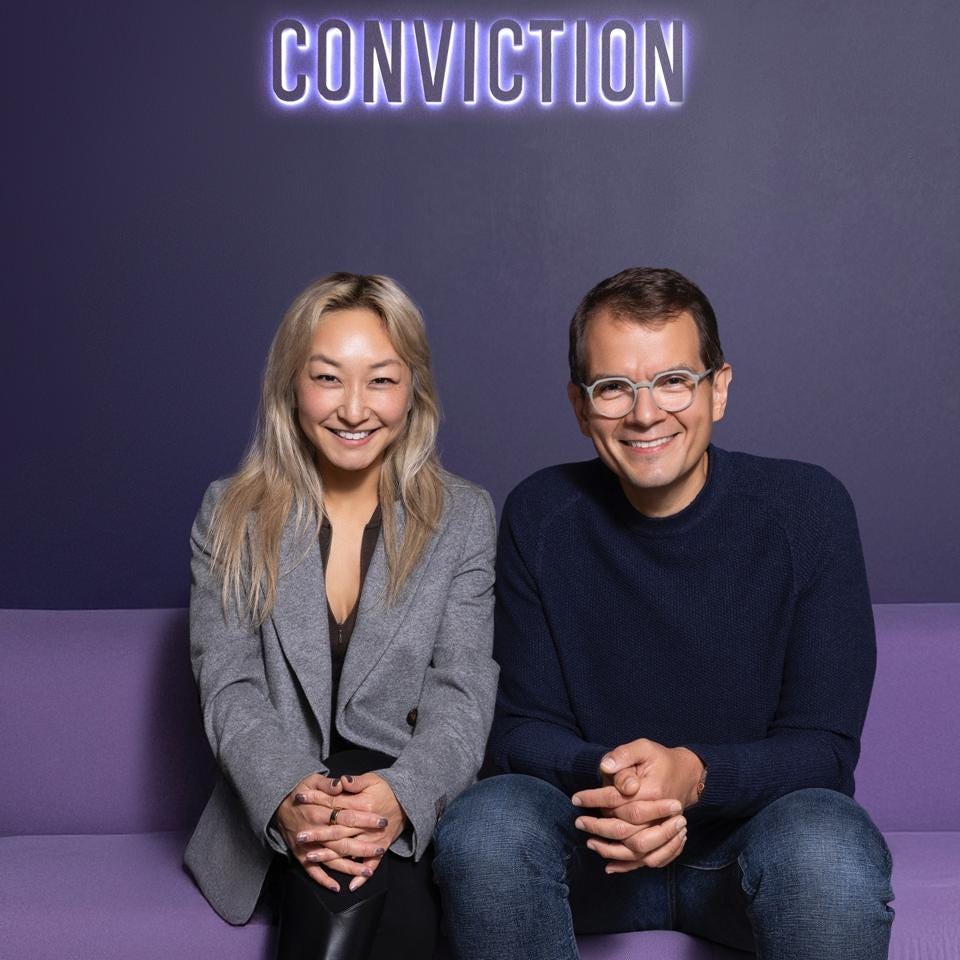 Portrait of Sarah Guo and Mike Vernal sitting together on a purple sofa against a matching backdrop, smiling at the camera. Portrait of Sarah Guo and Mike Vernal sitting together on a purple sofa against a matching backdrop, smiling at the camera.