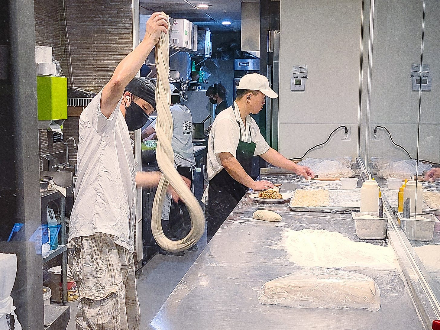 chefs hand pulling noodles