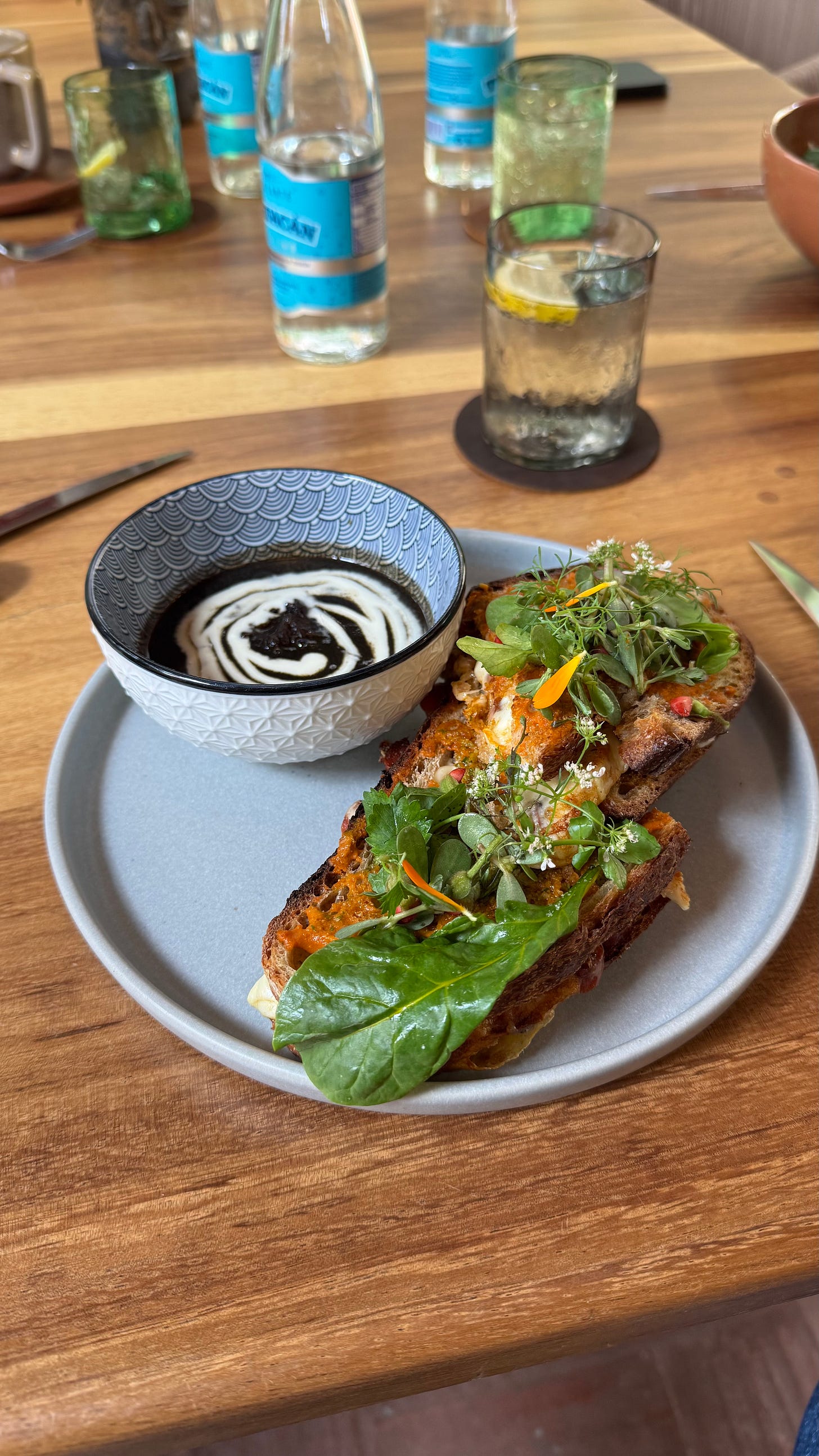 A sandwich and a bowl of black looking soup