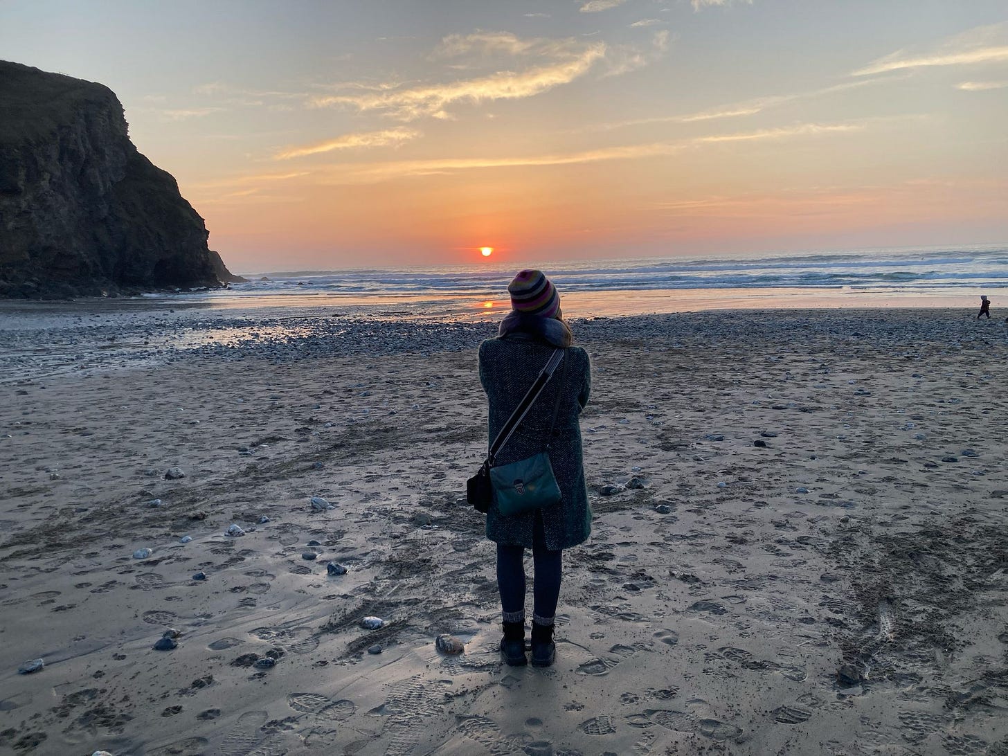 Back view of author on a beach at sunset on a cold spring day in Cornwall, England