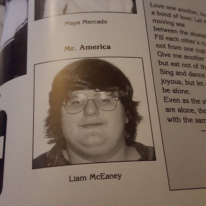 A very overweight Liam with serial killer glasses and long hair with a unibang like Zooey Deschanel in New Girl. The headline is "Mr. America" and the caption misspells his name as Liam McEaney. A very overweight Liam with serial killer glasses and long hair with a unibang like Zooey Deschanel in New Girl. The headline is "Mr. America" and the caption misspells his name as Liam McEaney.